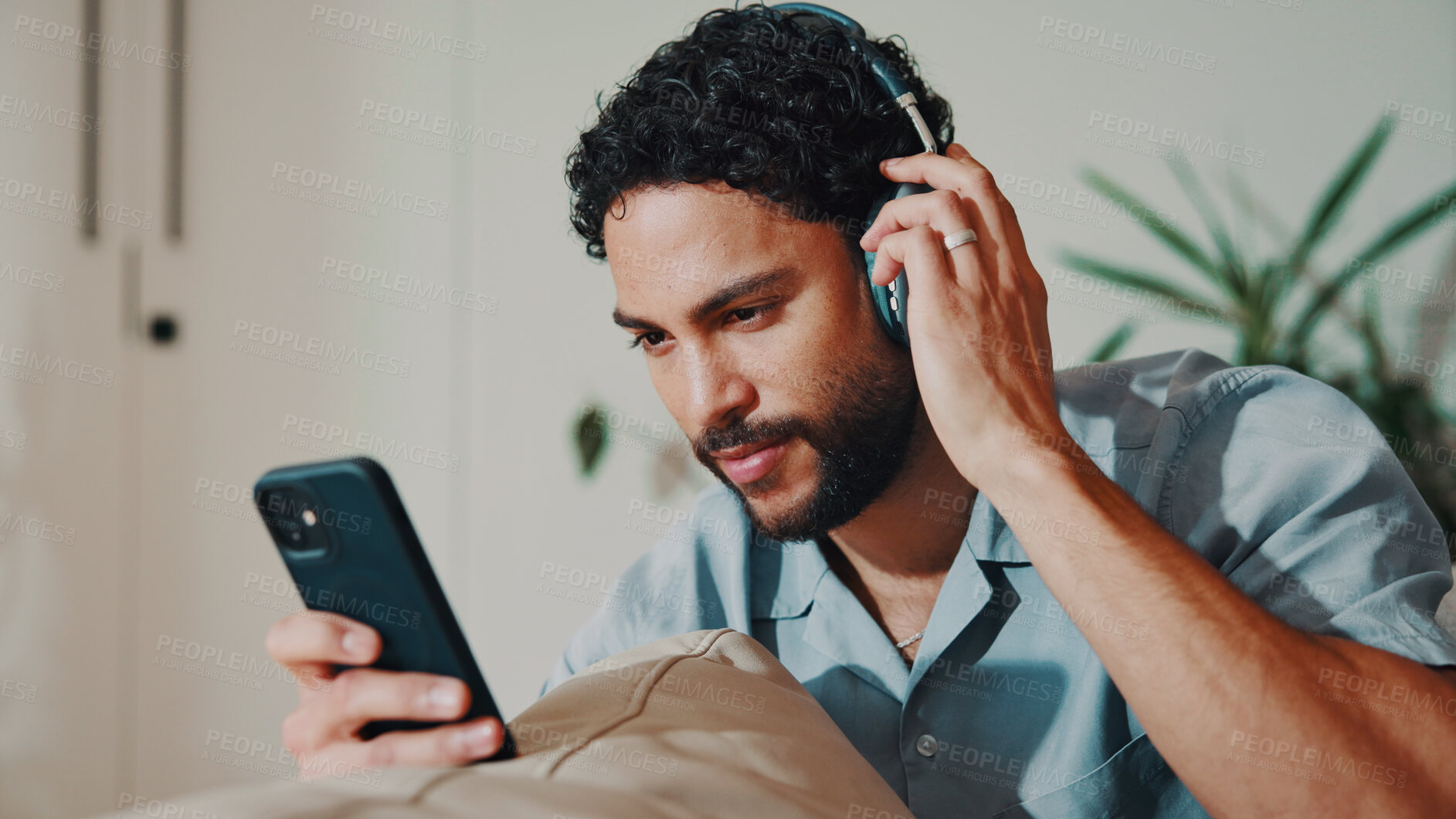 Buy stock photo Man, smile and headphones or phone on home sofa for streaming music, podcast or online subscription. Happy, audio playlist and male person relax on couch with mobile app, technology and sound