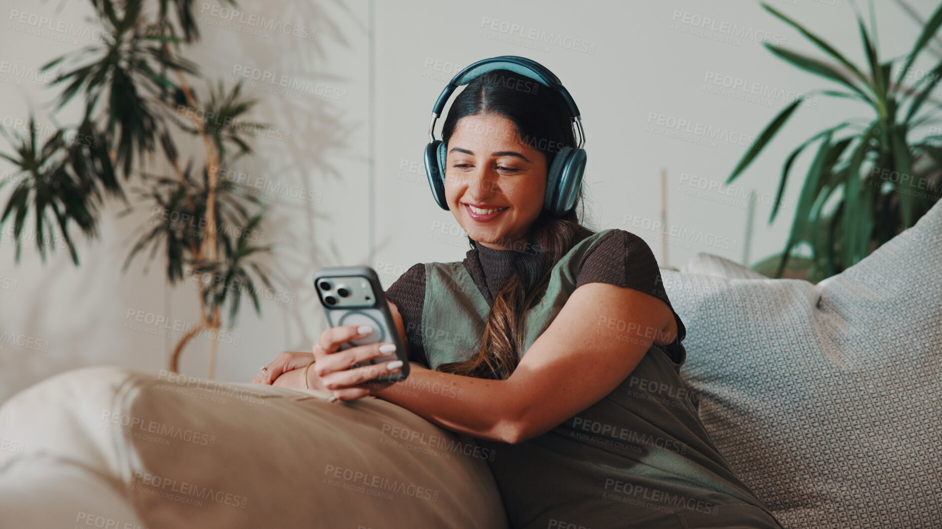 Buy stock photo Woman, happy and headphones or phone on home sofa for streaming music, podcast or subscription. Smile, audio playlist and female person relax on couch with mobile app, technology and sound online
