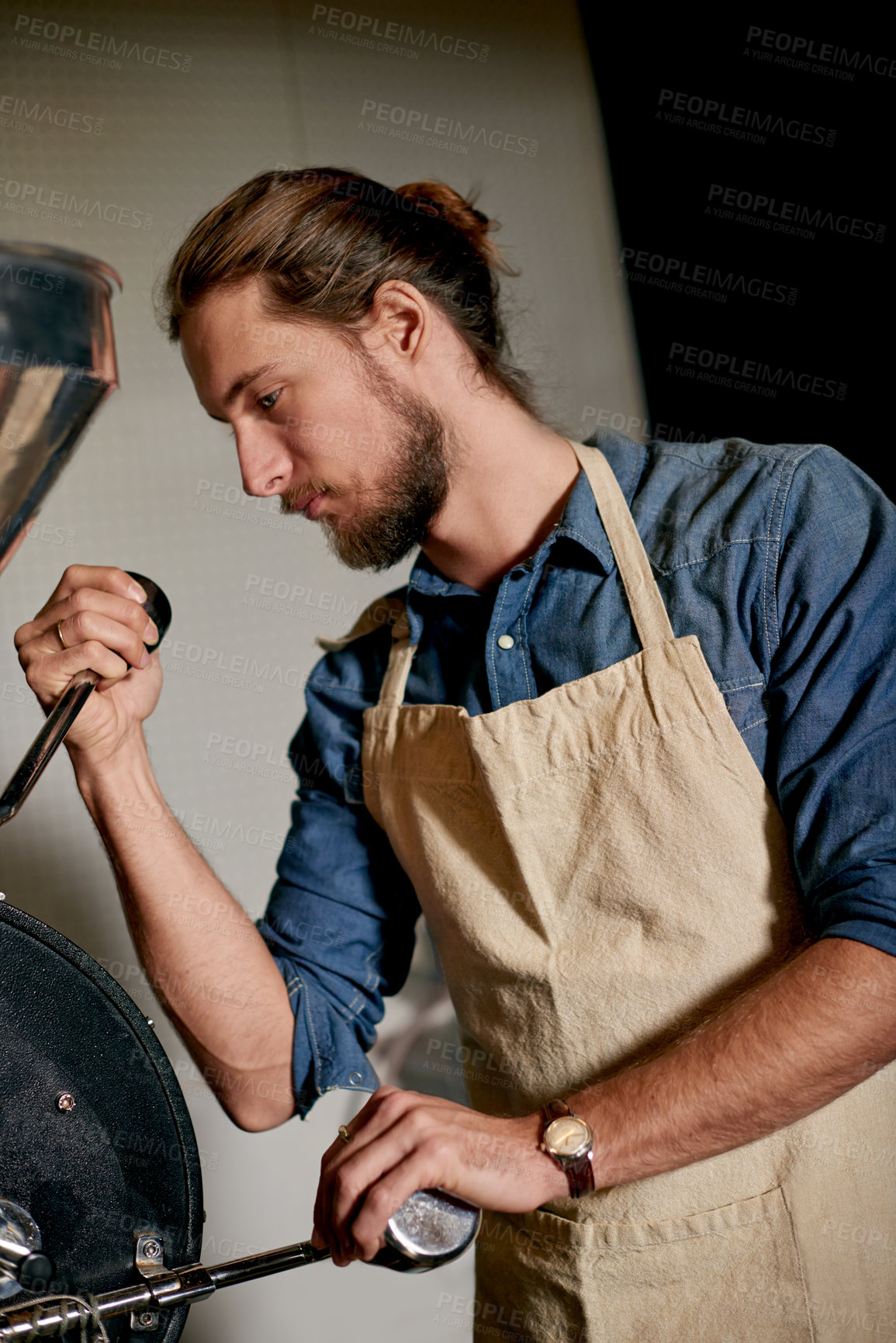 Buy stock photo Man, apron and equipment in coffee roastery for roasting, inspection or quality control for distribution. Small business, master roaster or machine with lever for flavor enhancing or bean preparation