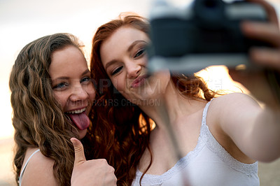 Buy stock photo Girl, friends and selfie with camera outdoor, thumbs up or gesture for social media or memory at sunset. Digital photography, people and tongue out for picture, vacation or weekend break together