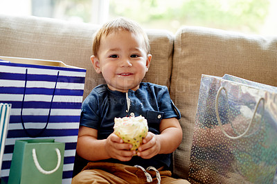 Buy stock photo Portrait, toddler and eating cupcake at birthday party, celebration and dessert on special occasion. Child, smile and cake with gift for event, family tradition and sweet snack for milestone at house