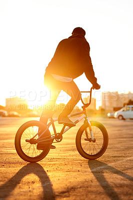 Buy stock photo Balance, city and sunset with man on BMX for adrenaline, exercise or extreme sports outdoor. Bike, flare and training with rider on street in urban town for action, hobby or practice from back