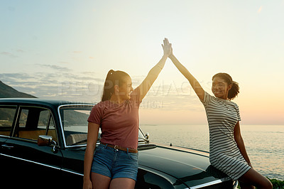 Buy stock photo Shot of two young women giving each other a high five on a road trip