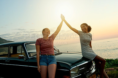 Buy stock photo Shot of two young women giving each other a high five on a road trip