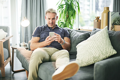 Buy stock photo Happy man, phone and texting on sofa in home, relax and scroll for web chat in living room. Mature person, smartphone and smile on couch with mobile app, notification or social network at apartment