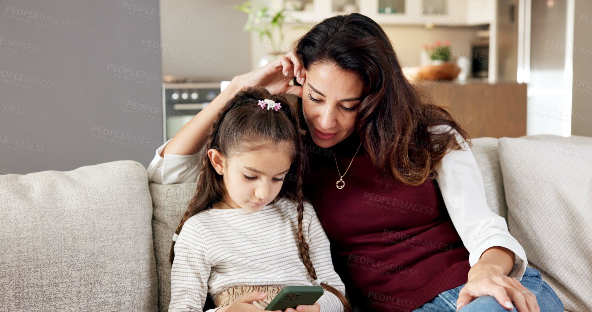 Buy stock photo Mom, child and mobile game in home with phone, bonding together and learn how to play for knowledge. Woman, daughter and supervision on sofa with tech, parent care and online gaming for education.