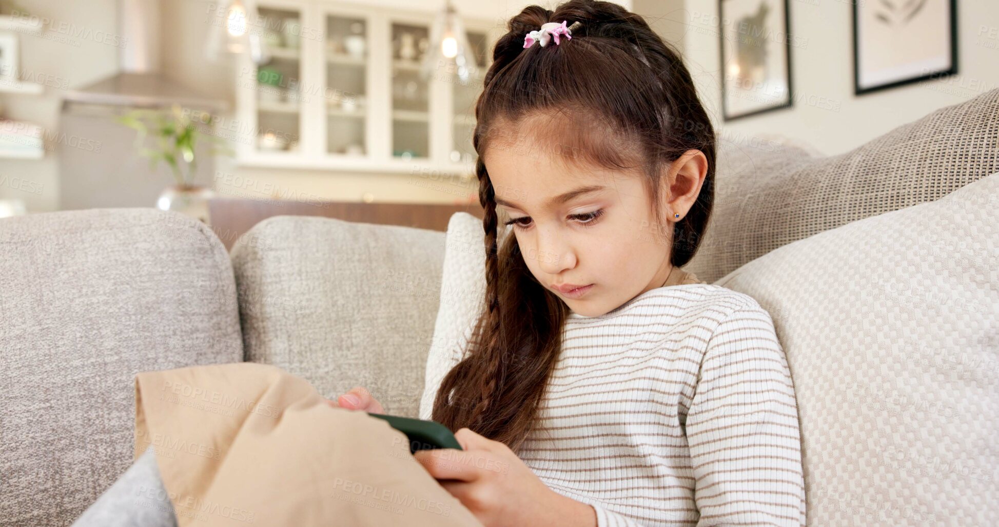 Buy stock photo Girl, child and playing with phone on sofa for online streaming, gaming or entertainment in home. Kid, user or interaction with technology or app for mobile network service or connection in house