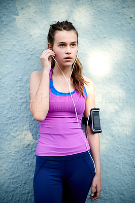 Buy stock photo Fitness, rest and girl on wall with earphones, podcast or  audio streaming for wellness practice. Health, break and teenager on plaster background with tech, training or workout music for sports goal