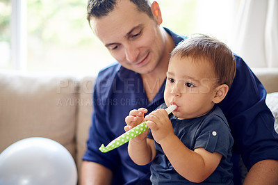 Buy stock photo Balloon, birthday or whistle with dad and son on sofa in living room of home for milestone. Development, growth or party blower with boy child and single parent man in apartment for bonding as family