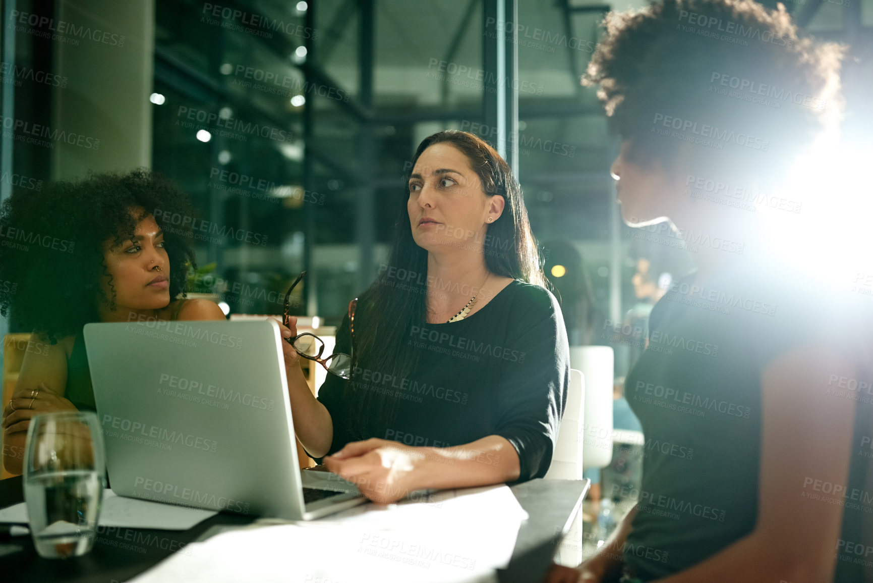 Buy stock photo Women, meeting and laptop at startup, night and discussion with review, insight and project at media company. People, editor and team with documents, talk or feedback with computer at creative agency