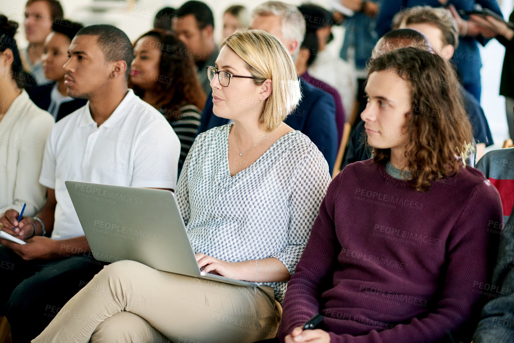 Buy stock photo Woman, laptop and listen in audience at conference with typing notes, agenda and attention at company event. Business people, crowd and employee with computer, seminar and presentation at convention