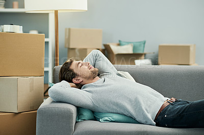 Buy stock photo Man, new home and relief on couch, moving and tired with smile for boxes in living room at property. Person, happy and relax for rest, fatigue or exhausted on sofa for fresh start with real estate
