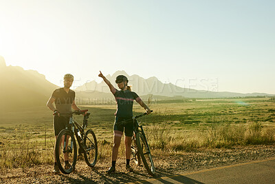 Buy stock photo Shot of a man and woman riding their bicycles in the countryside