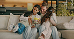 Happy, popcorn and parents with kids on sofa for bonding, playful and relax for movie together. Home, family and children with mom, dad and hug with snack for watching tv, film or cartoon for weekend
