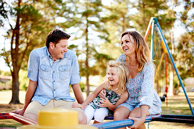 Buy stock photo Father, mother and child on roundabout in playground for family weekend fun, happy bonding or love. Smile, caring man or woman with girl on playing equipment together, park visit or support in summer