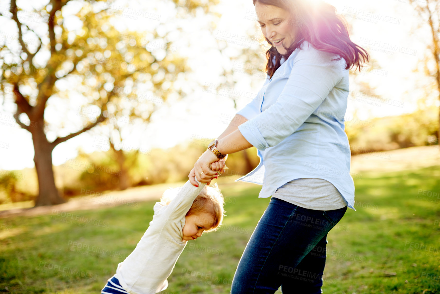 Buy stock photo Mother, spin child and play at park with smile, bonding and flare with love, fun and summer in nature. People, mom and daughter with games for toddler, swing or holding hands with care in Portugal