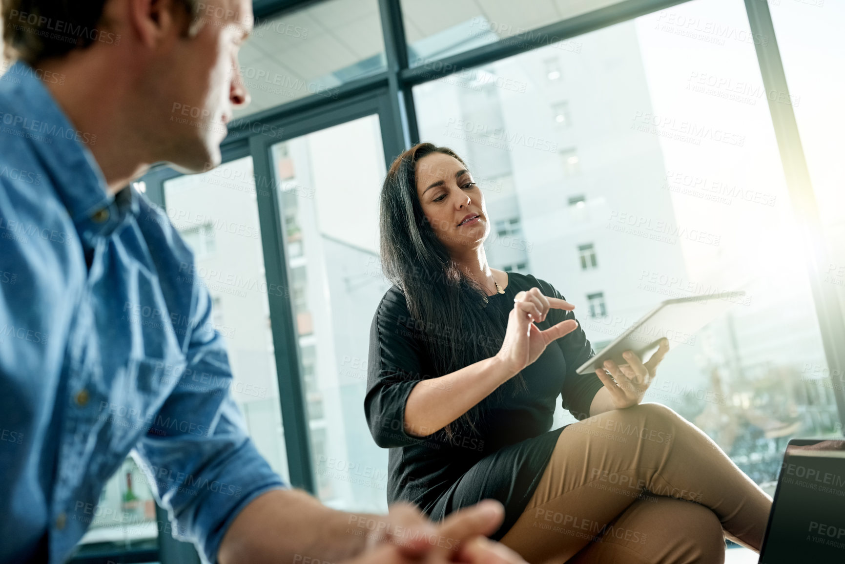 Buy stock photo Woman, tablet and team in discussion at office meeting for planning, review or low angle at media company. People, tech and application for project, brainstorming or collaboration at creative agency