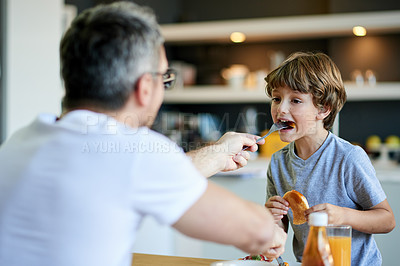 Buy stock photo Home, breakfast and father with son, feeding and bonding together with nutrition, love and juice. Family, apartment and dad with happy boy, morning food and parent with healthy meal, help and eating