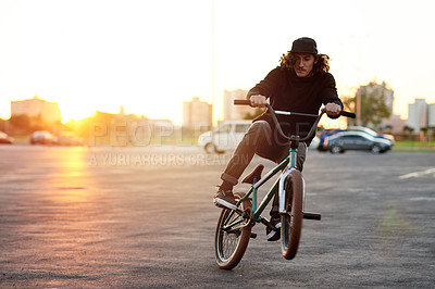 Buy stock photo Urban, trick and man on bicycle at sunrise for cycling, training skill and fitness in city to practice. Cool person, athlete or stunt biker at town in morning for wheelie, sports or outdoor biking