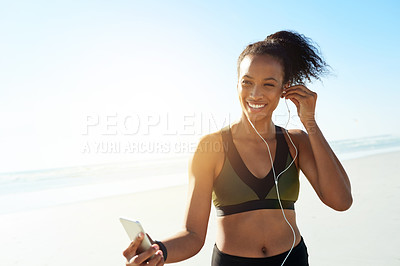 Buy stock photo Exercise, smile and woman with earphones at beach for fitness, music or workout podcast. Phone, runner and athlete with tech for marathon training, space and streaming audio or getting ready by ocean