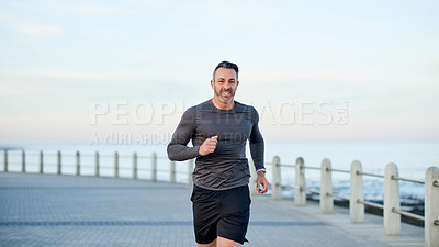 Buy stock photo Mature man, running and portrait on beach promenade, sports workout and activity for mobility health. Male person, physical challenge and training for marathon, outdoor and cardiovascular exercise