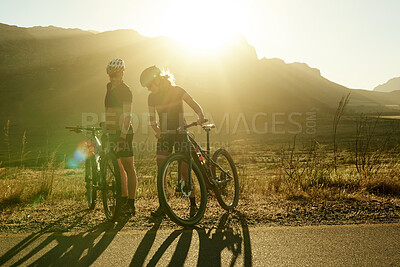 Buy stock photo Shot of a man and woman riding their bicycles in the countryside