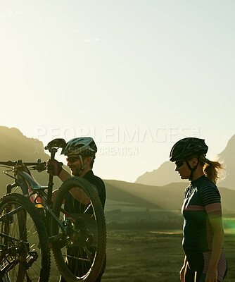 Buy stock photo Shot of a man and woman riding their bicycles in the countryside
