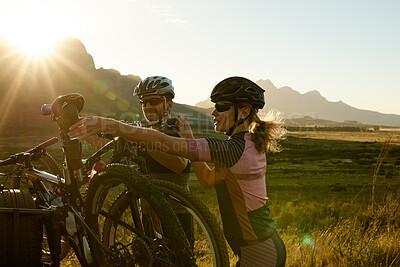 Buy stock photo Shot of a man and woman riding their bicycles in the countryside