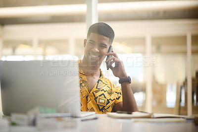 Buy stock photo Shot of a young businessman talking on a cellphone while working on a laptop in an office