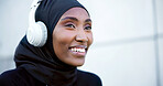 Outdoor, fitness and muslim woman with headphones, listen to radio or streaming song with happiness. Hijab, active and black person with music, thinking and smile on audio break with space in city