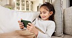 Happy, girl or child with phone on sofa for online streaming, gaming or entertainment in home. Kid, user or interaction with smile, technology or app for mobile network service or connection in house