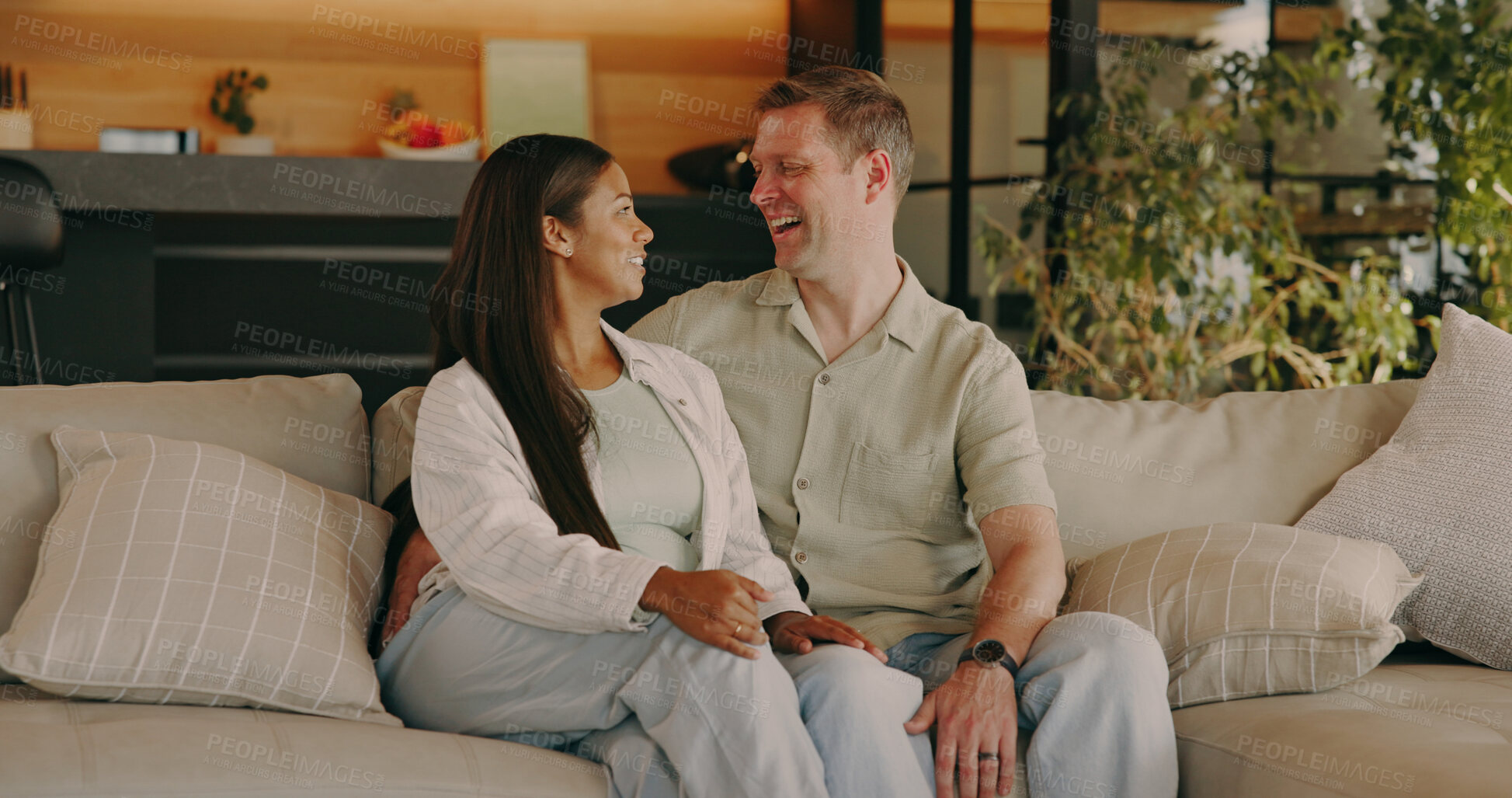 Buy stock photo Couple, relax and talking at house with smile, love and romantic partner on valentines day. Happy, interracial people and discussion in lounge for romance, embrace spouse and affection for commitment
