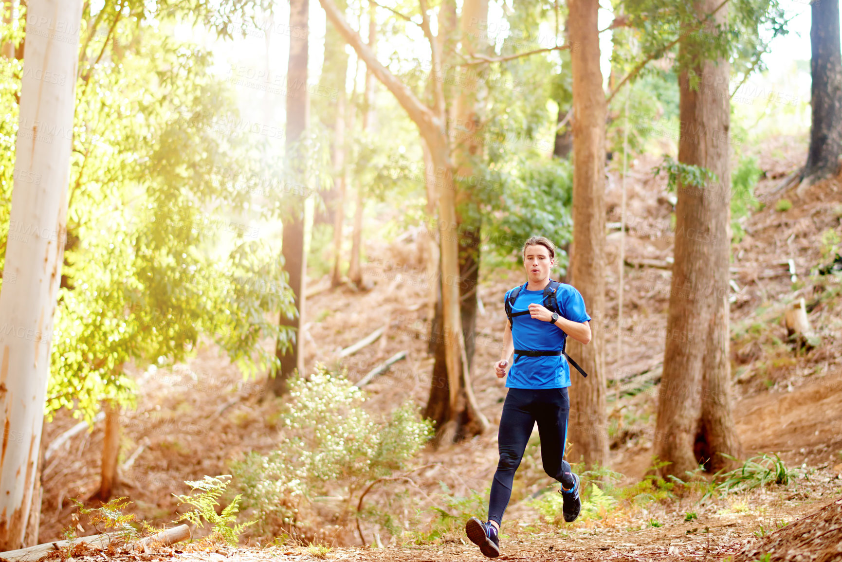 Buy stock photo Fitness, man and running in forest with exercise for marathon competition, endurance challenge and cardio. Trail runner, athlete and backpack in woods for training performance, wellness and workout