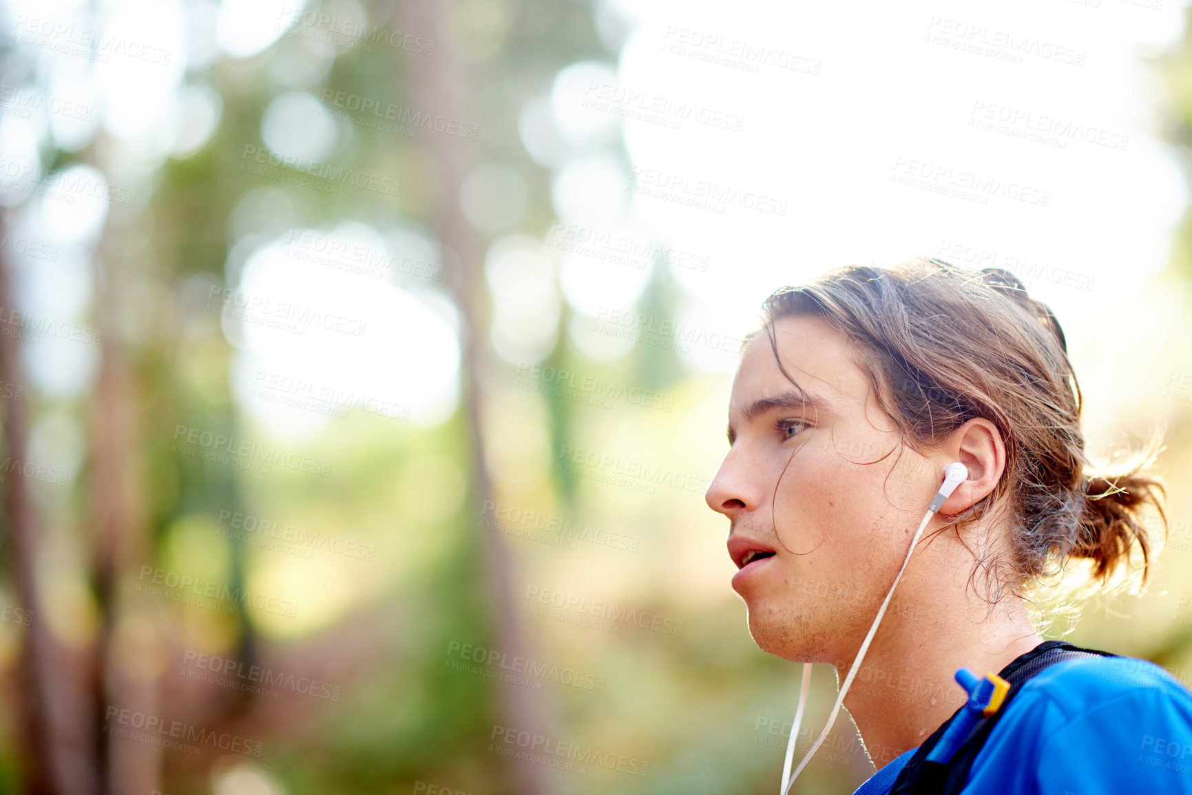 Buy stock photo Breathing, runner and man with earphones, break and tired on jog in nature, streaming and playlist. Outdoor, athlete and person with radio for entertainment, resting and guy with fatigue in morning