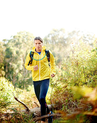 Buy stock photo Running, athlete and man with earphones, forest and active with backpack in nature, wellness and music. Outdoor, runner and person with tech for playlist, energy and listening to radio for exercise