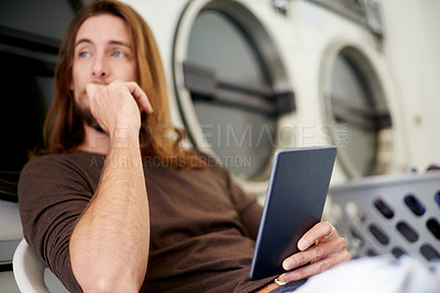 Buy stock photo Laundry, thinking and man with tablet, washing and relax with digital app, bored and daydreaming. Person, weekly chore and customer with tech, decision and internet with online schedule and wonder