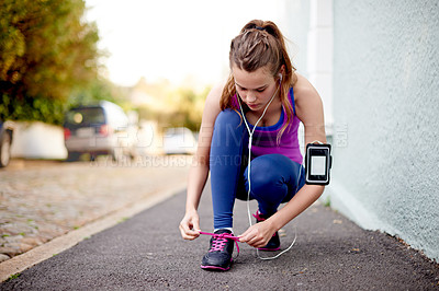 Buy stock photo Shot of a teenage girl tying her shoelaces before a run
