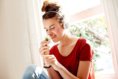 Buy stock photo Girl, flower and relax in home with headphones, peace and Valentines day gesture with smile. Teenager, wireless technology and smell rose at window with love music, good mood and happy memories