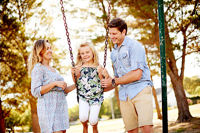 Buy stock photo Parents, girl and happy on swing at park for playing together, bonding and vacation weekend. Family fun, people and portrait on playground equipment for sensory stimulation, childhood memory or trust