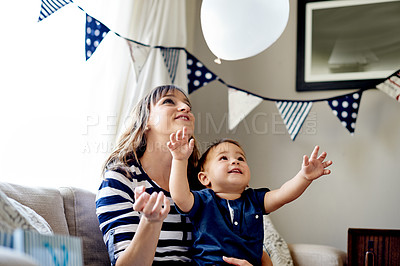 Buy stock photo Balloon, playing and mother with baby on sofa in home for bonding, connection or family time. Happy, birthday party and mom with boy child for sensory development at celebration in living room.