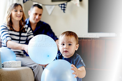 Buy stock photo Portrait, toddler and balloon in home with parents for party with celebration, milestone and together in lounge. Mom, dad and kid playing with decorations for birthday event with love in family house