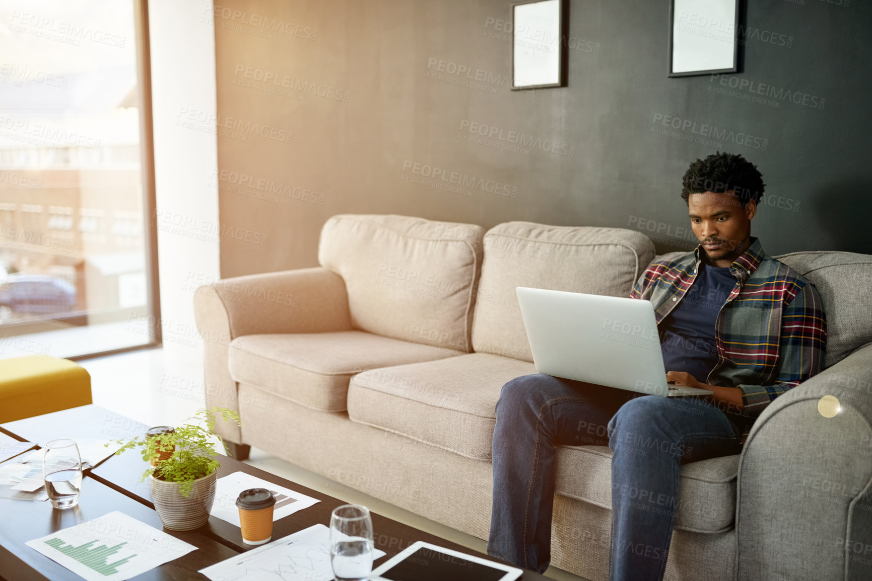 Buy stock photo Black man, laptop and typing on sofa, office or notification for project funding at interior design company. Person, computer and creative process for renovation job at property development agency
