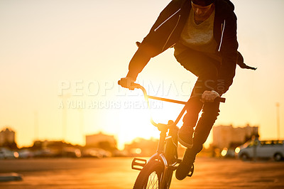 Buy stock photo Sunset, adventure and man on bicycle in city with tricks, fun or skills for activity with travel. Adrenaline, practice and person on bike training for competition, challenge or race in urban town.