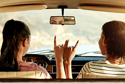 Buy stock photo Women, friends and back with road trip in car for hand gesture, horns or journey together. Female person, traveler or bonding with rock on, sign or symbol for drive, adventure or vacation in vehicle