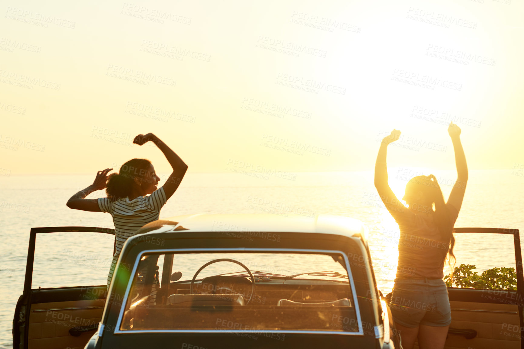 Buy stock photo Shot of two happy young women enjoying a road trip