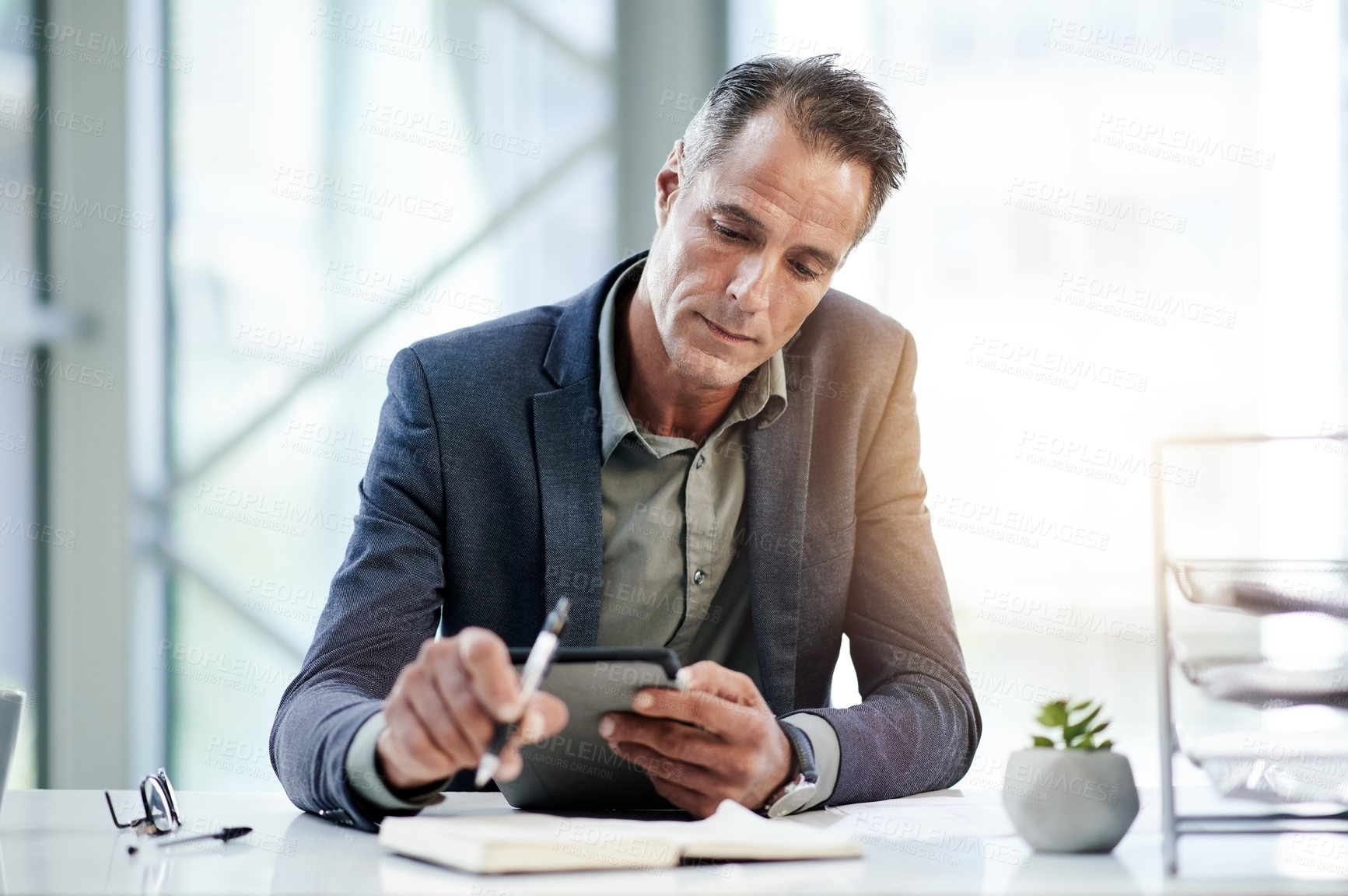 Buy stock photo Notebook, news and businessman on tablet in office for online report, finance and audit. Mature, review or banker on touchscreen in financial agency for equity, stock research and investment