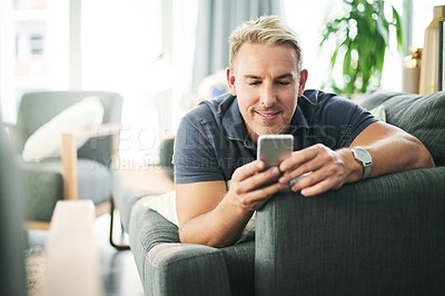 Buy stock photo Man, phone and laying on couch in home, relax and happy with chat, notification or texting in lounge. Mature person, smartphone and search mobile on app for video, smile and social media at house