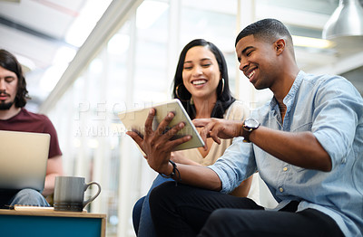 Buy stock photo Shot of two businesspeople using a digital tablet together in an office