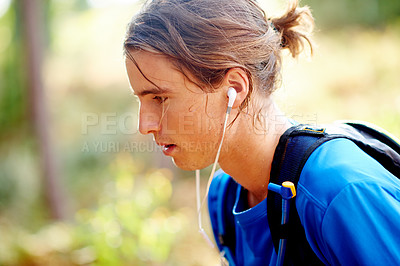 Buy stock photo Breathing, tired and man in forest, runner and fitness with challenge, training and listening to music. Profile, healthy person and athlete in woods, practice and sweating with endurance and fatigue