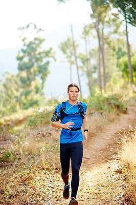 Buy stock photo Fitness, man and running in forest with earphones for workout playlist, cardio wellness or music album. Athlete, runner and training on mountain trail with breathing exercise, audio podcast or health